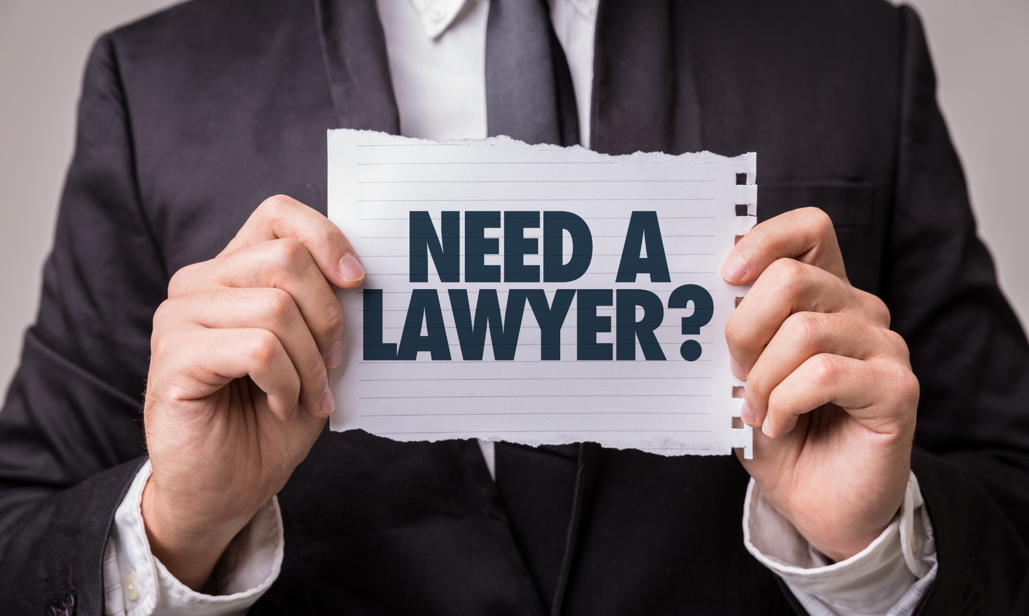 Persona che mostra un cartello con la scritta Need a Lawyer?